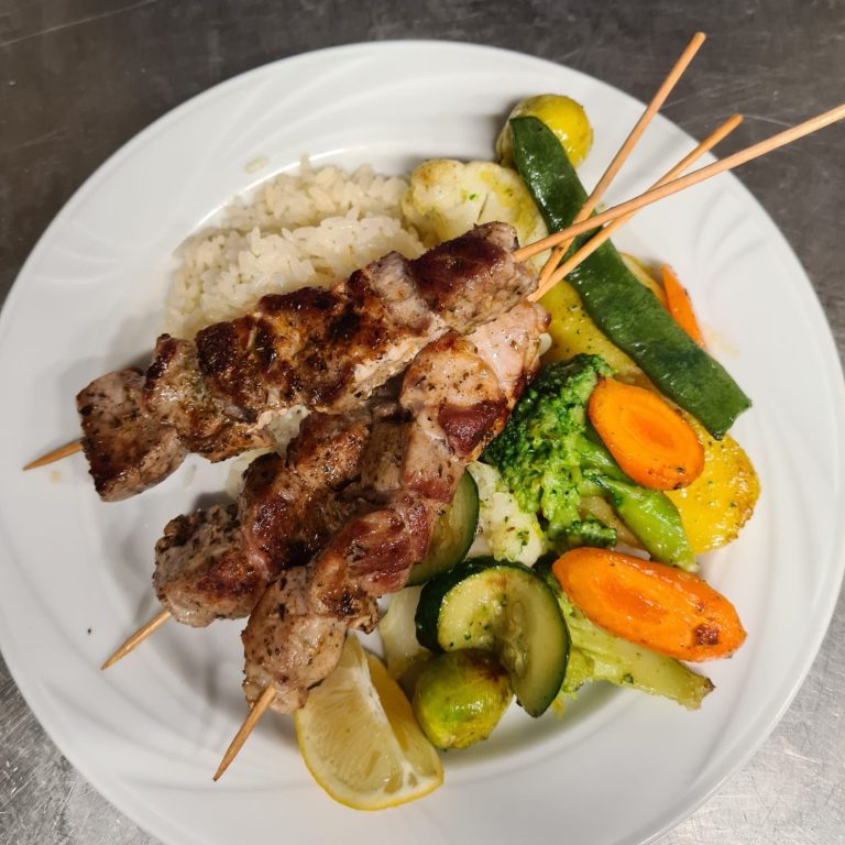 Grillspieße mit Gemüse und Reis auf einem weißen Teller.