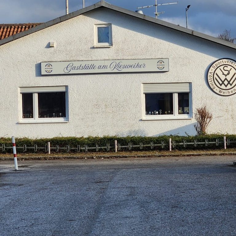 Gebäude mit dem Schriftzug "Gasthof zum Kiesweiher" und einem runden Logo an der Fassade.